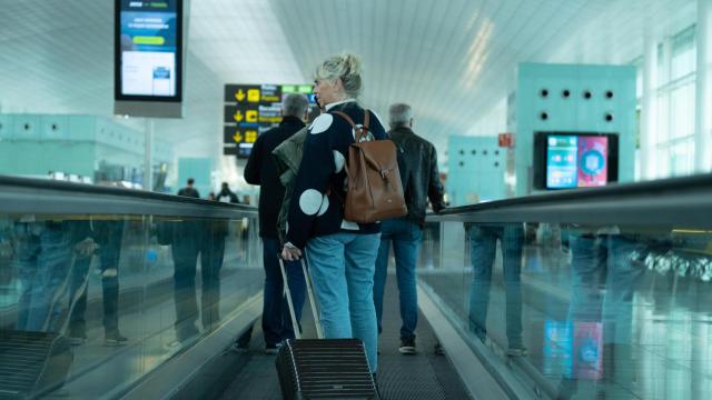 Una mujer camina con su maleta en el aeropuerto de El Prat