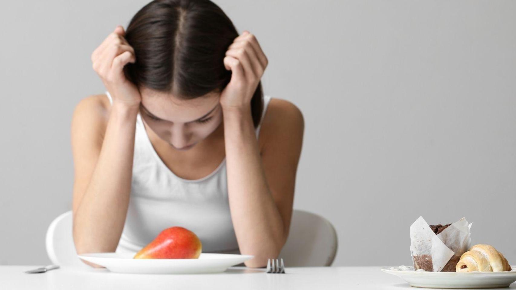 Una joven mira la comida con ansiedad