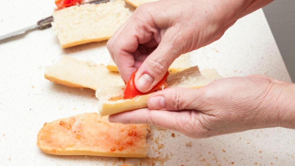 Una persona haciendo un pan con tomate