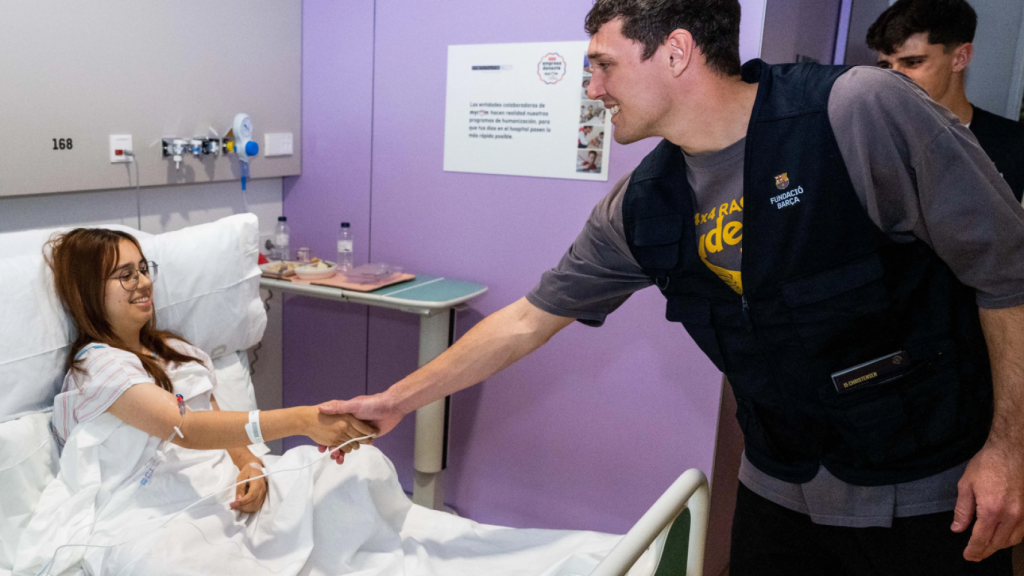 Andreas Christensen y Pau Víctor saludan a una paciente en el Hospital Sant Joan de Déu