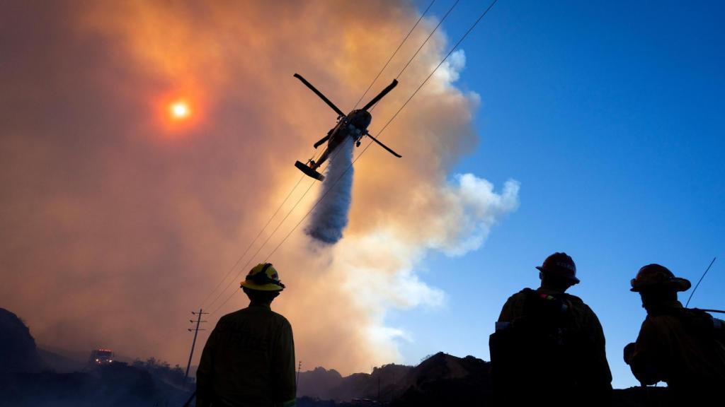 Un helicóptero lanza agua sobre el fuego de Los Ángeles