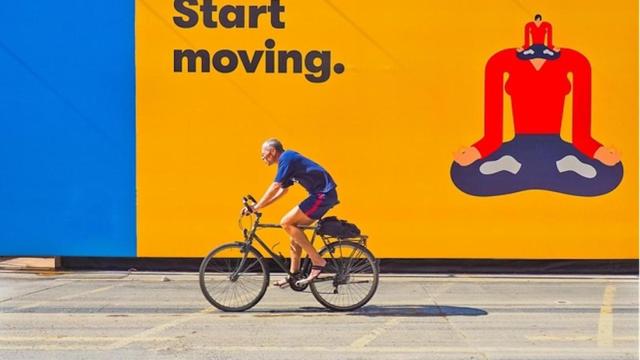 Ciclista frente a un cartel publicitario