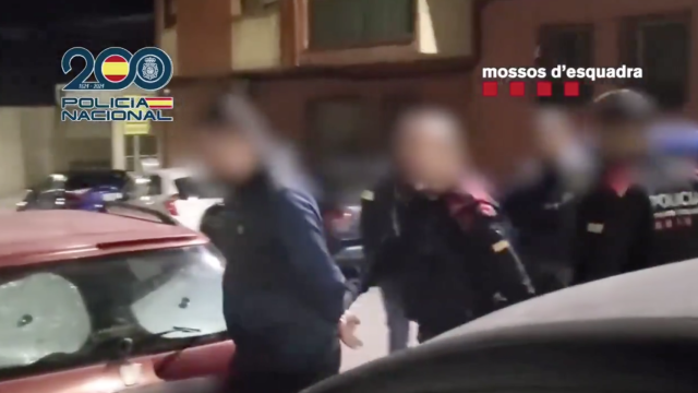 Agentes de los Mossos d'Esquadra y la Policía Nacional con uno de los detenidos