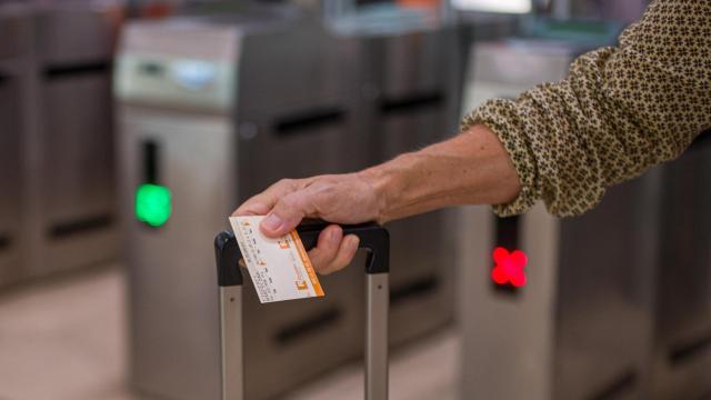 Una viajera de Rodalies sostiene un billete de tren y su maleta