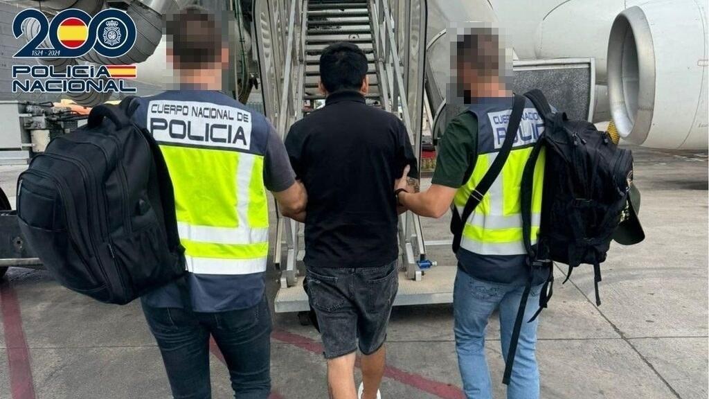 Dos policías conducen a uno de los ciudadanos deportados hasta el avión