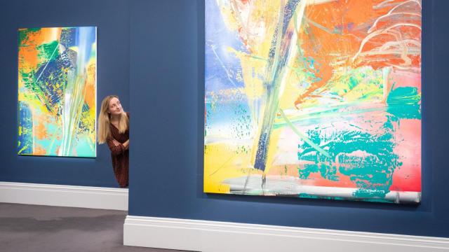 Un empleado de Sotheby's observa obras de un trío de pinturas abstractas de Gerhard Richter