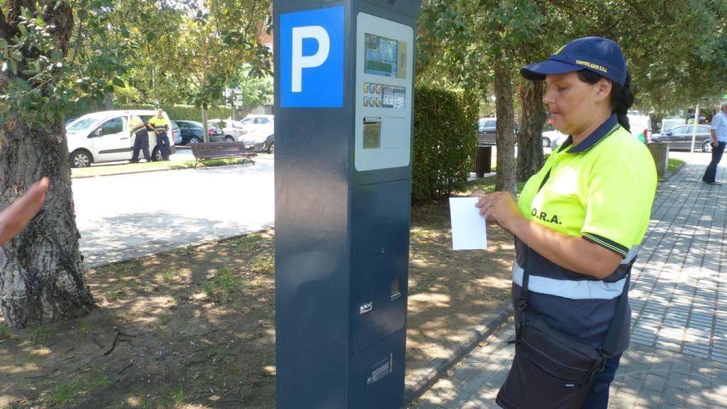 Una revisora frente a un parquímetro