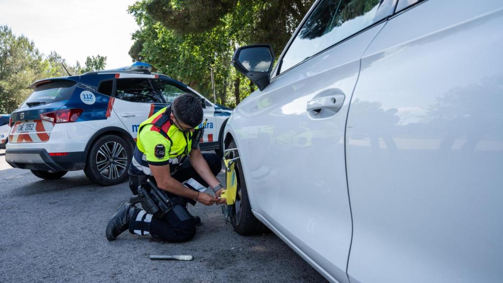 Agente de la Unidad de Tráfico colocando el cepo en el vehículo intervenido