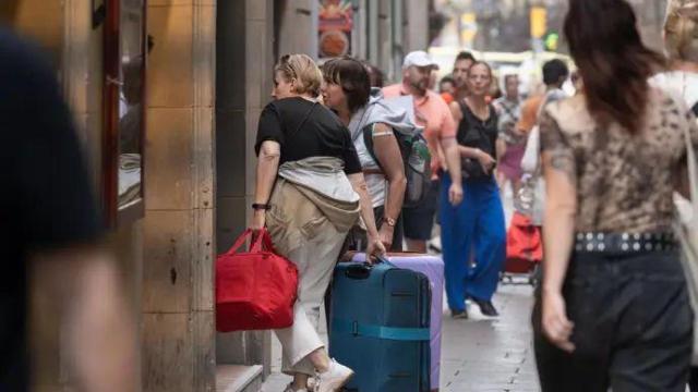 Varios turistas con maletas en el centro de Barcelona.