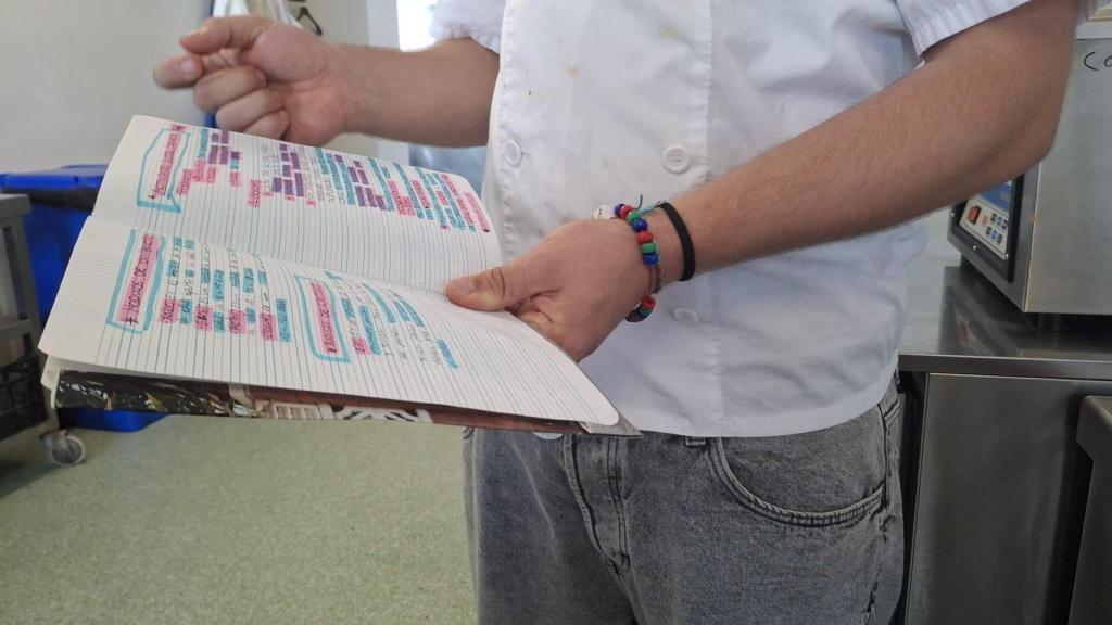 El joven del centro de justicia juvenil Can Llupià enseña el cuaderno en el que tiene anotadas todas las actividades del verano