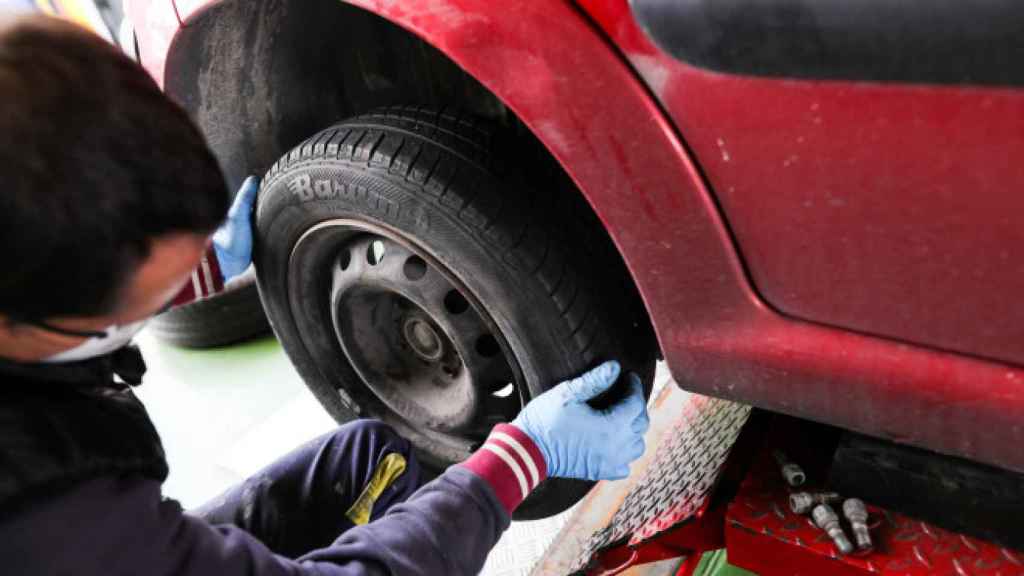 Un trabajador en un taller cambia la rueda a un coche / EP