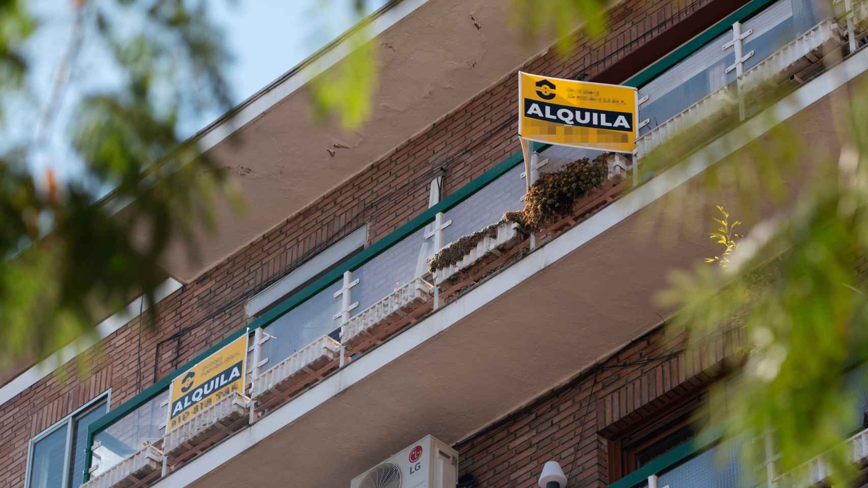 Fachada de un edificio con un cartel de una vivienda en alquiler. / EP