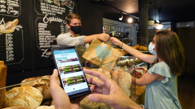 Un local entrega un pack con excedente de comida a un cliente / TOO GOOD TO GO