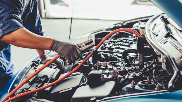 Un operario repara un coche en un taller / EP