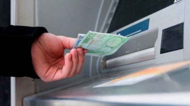 Una persona saca dinero de un cajero automático, en una imagen de archivo / EFE