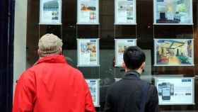 Dos personas observan precios de vivienda en una inmobiliaria. / EFE