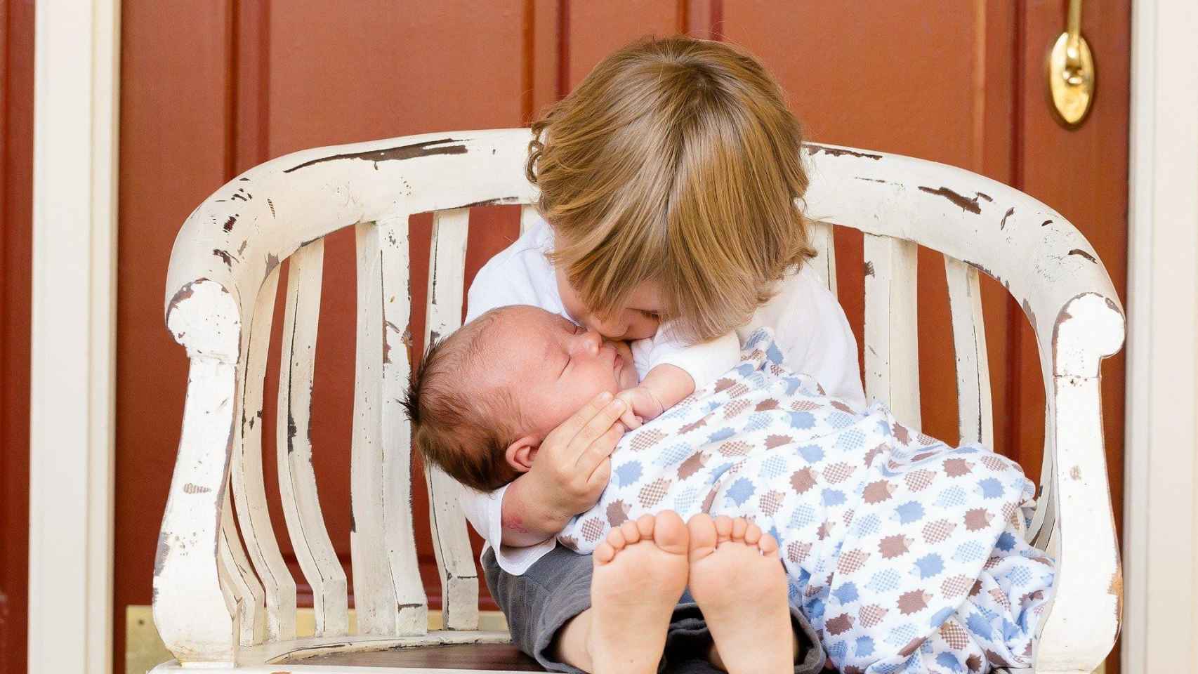 Un nio y un beb sentados en un banco / CG