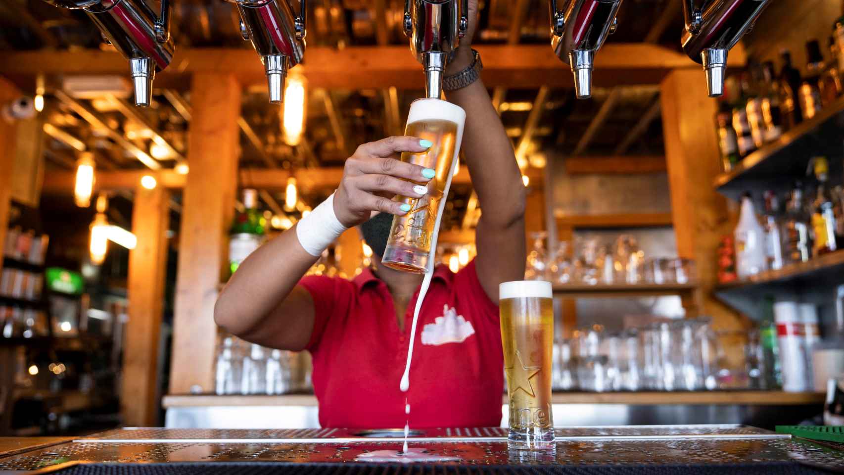 Una camarera tira una cerveza en un local de hostelera. / EFE