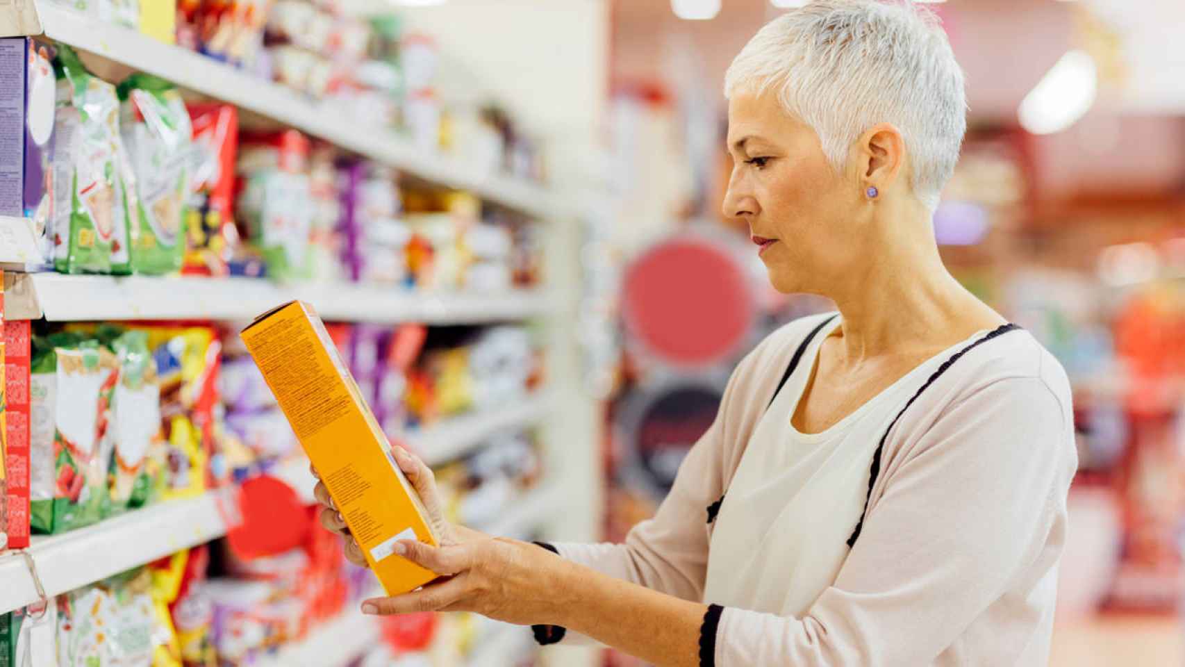 Una mujer observa un paquete de cereales.