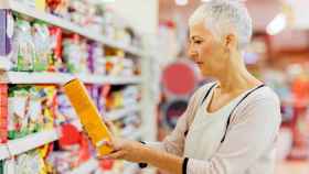 Una mujer observa un paquete de cereales.