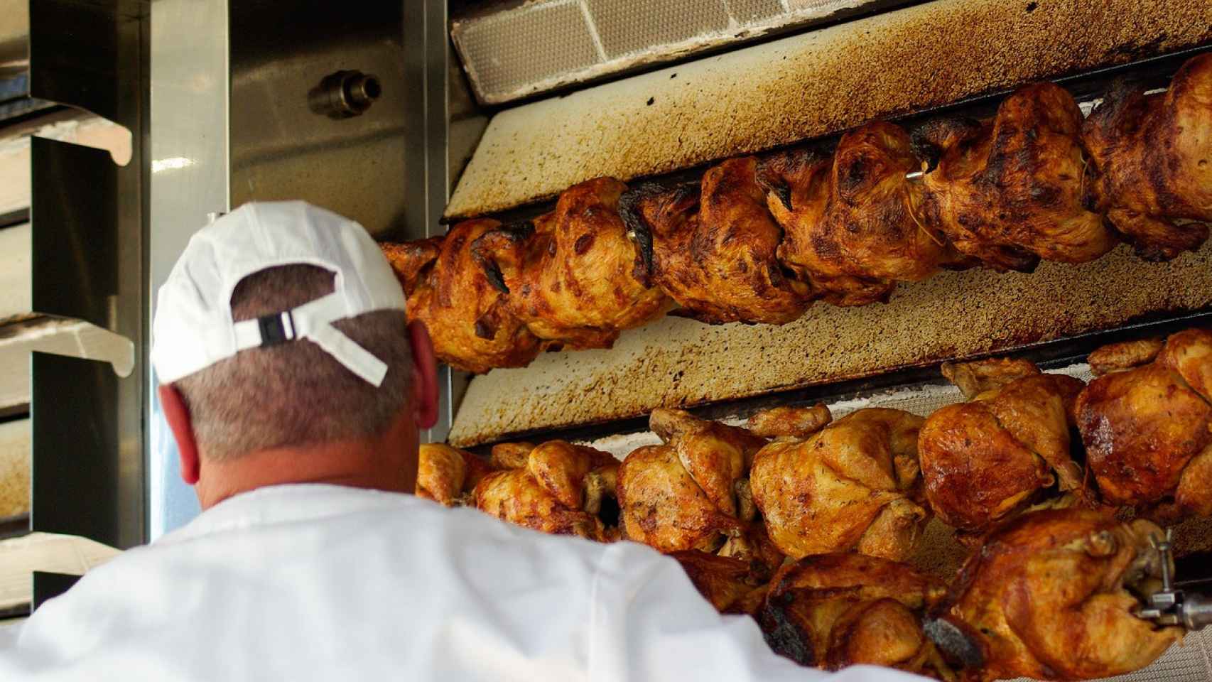 Un hombre asa unos pollos.