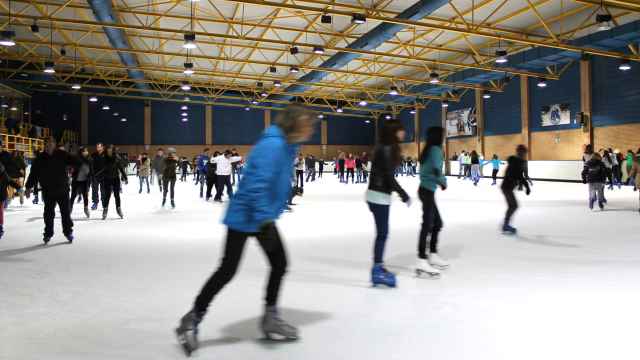 Varias personas disfrutan patinando en la pista de hielo.