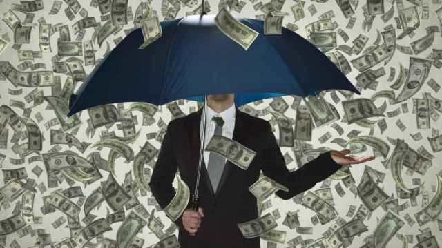 Un hombre bajo un paraguas protegiéndose del dinero.