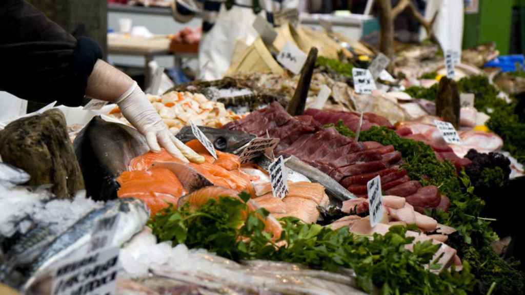 Una mujer selecciona pescado en un mercadillo.