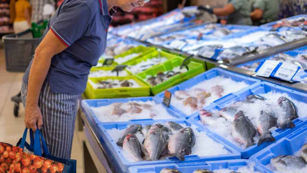 Un hombre selecciona los mejores pescados para su cena en un mercadillo.