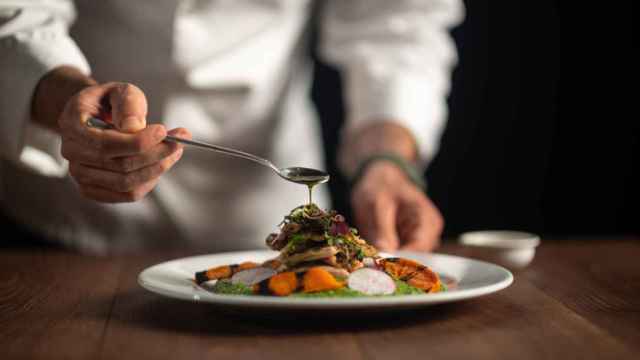 Un chef vierte una salsa sobre la comida.