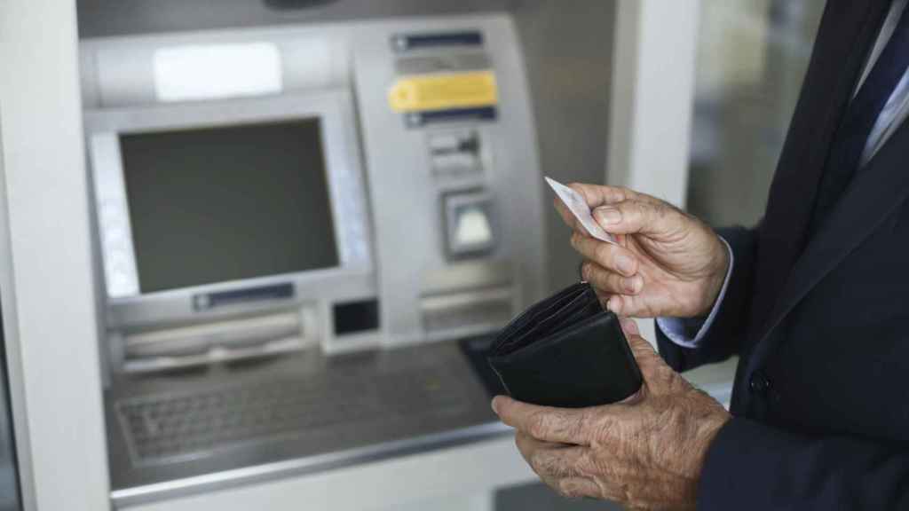 Un pensionista al cobrar su pensión en un cajero / GETTY IMAGES