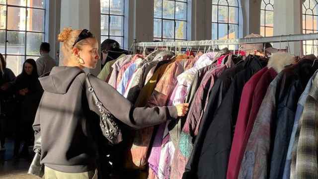 Una joven mira ropa en un mercadillo de ropa 'vintage'.
