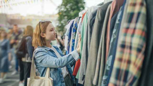 Una joven elige ropa en un mercado de segunda mano.