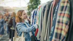 Una joven elige ropa en un mercado de segunda mano.