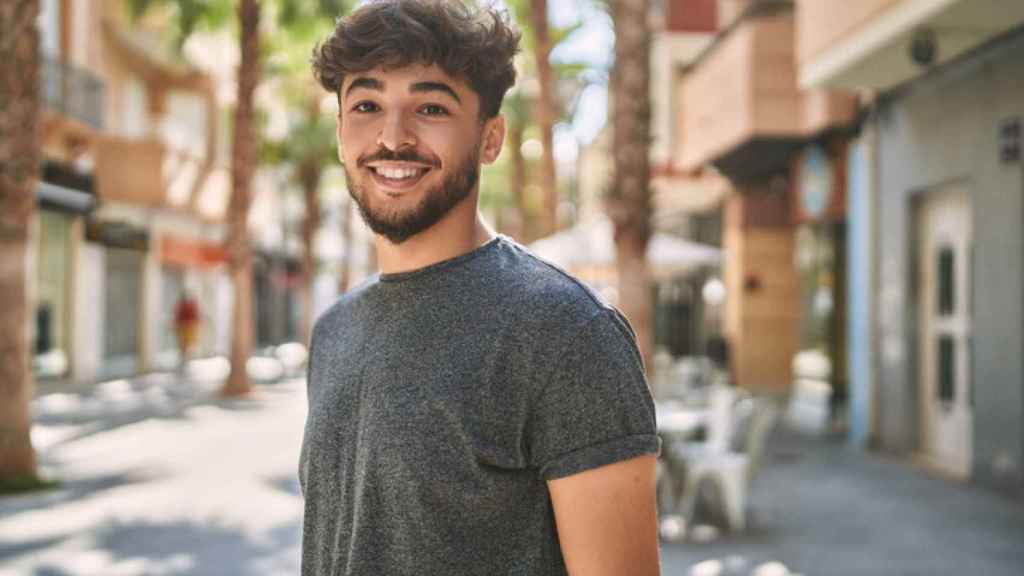 Un hombre joven mira a cámara sonriente.