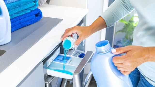 Una mujer agrega detergente a la lavadora.