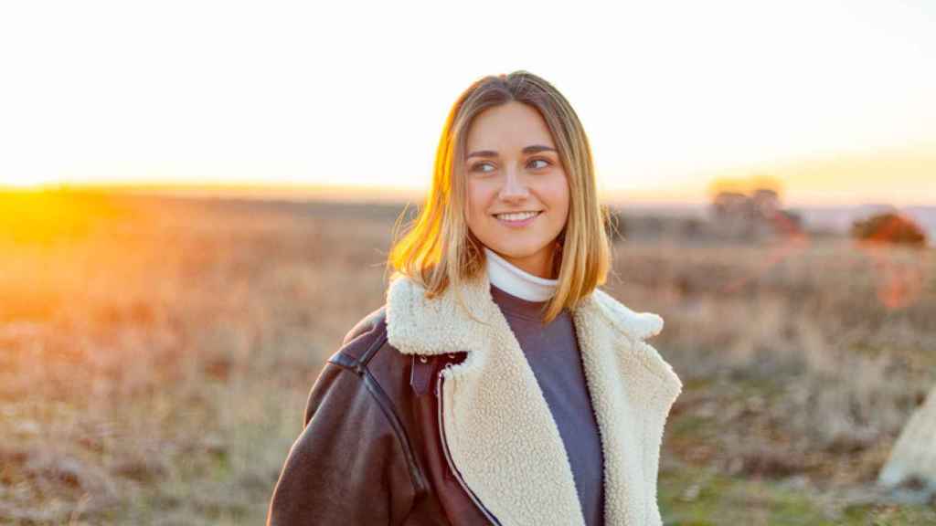 Una mujer joven sonríe en el campo.