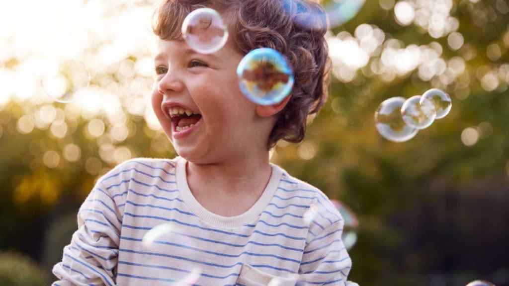 Un niño juega en el jardín a las pompas.