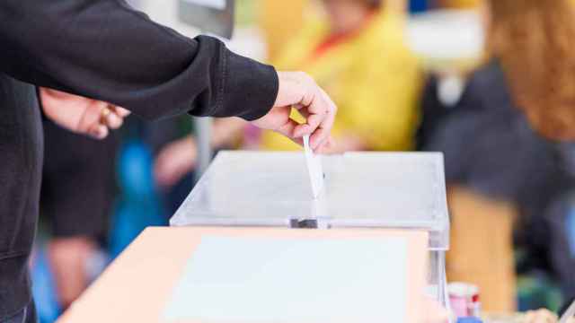 Un hombre introduce un sobre con su voto en una urna durante unas elecciones.