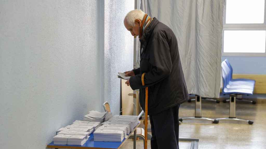 Un hombre elige papeleta para las elecciones al Parlamento Vasco, este domingo, en un colegio electoral en Bilbao.