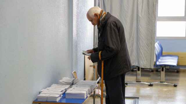 Un hombre elige papeleta para las elecciones al Parlamento Vasco, este domingo, en un colegio electoral en Bilbao.