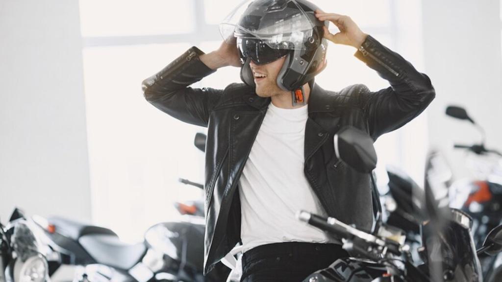 Un motorista se coloca el casco sobre la moto