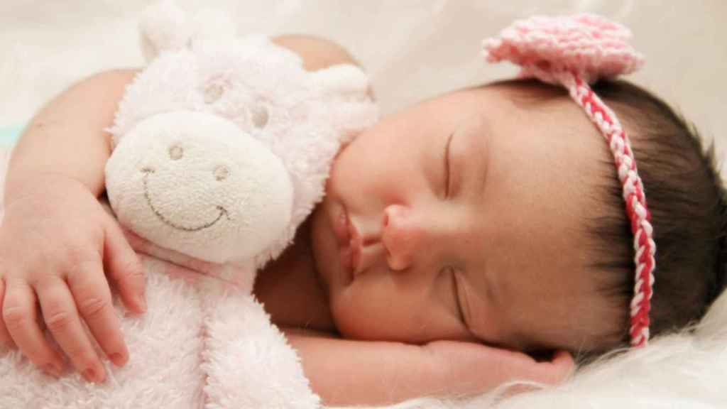 Una niña bebé durmiendo con su osito | PEXELS