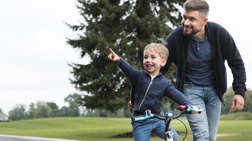 Padre e hijo aprendiendo a montar en bici / Freepik