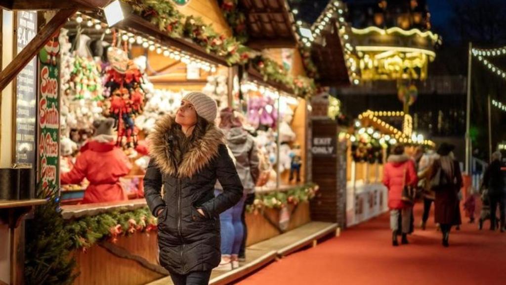 Una mujer se pasea por un mercado navideño.