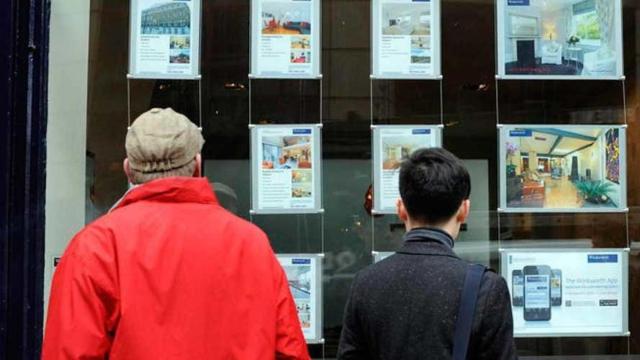 Dos personas observan precios de vivienda en una inmobiliaria. / EFE