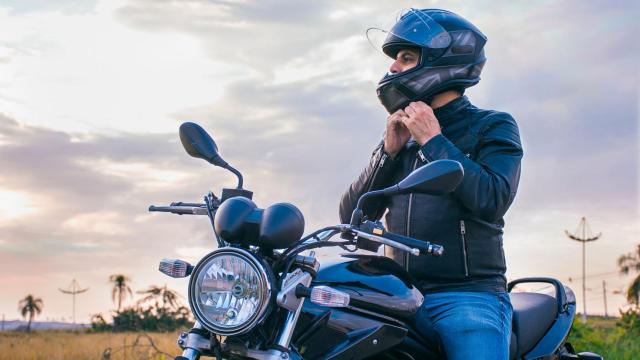 Un motorista posa mientras se quita el casco.