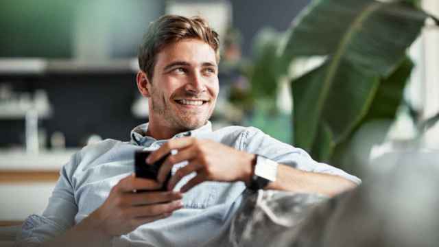 Un hombre sonriente sostiene una taza.