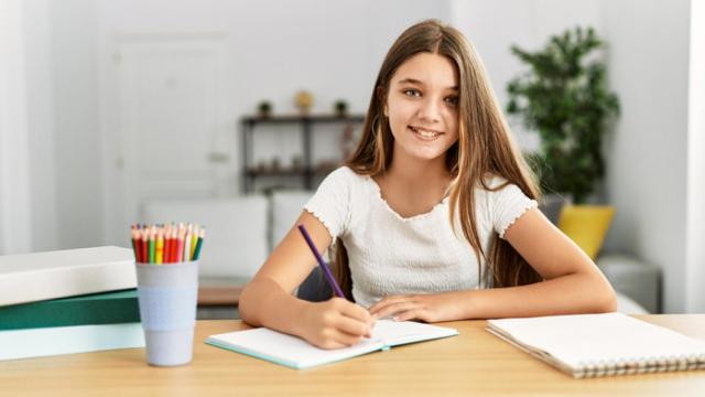 Una niña realiza unas tareas en la mesa.