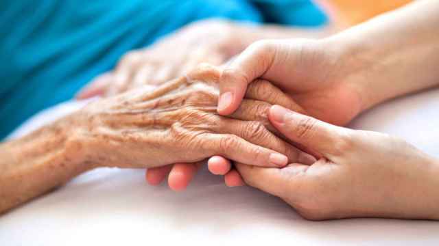 Una joven agarra la mano de una anciana.